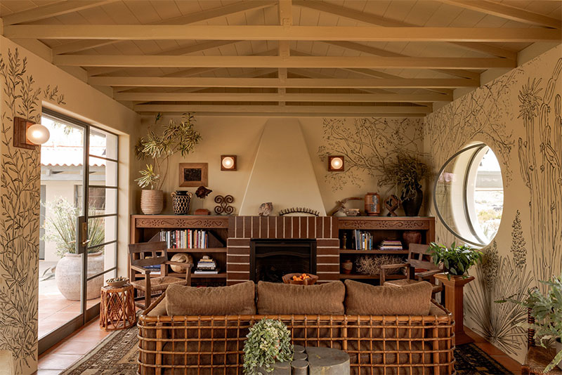 Hôtel Wren à Twentynine Palms : Le salon avec sa cheminée en brique et ses peintures murales de plantes du desert