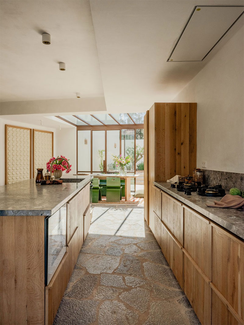 La cuisine avec ses meubles en bois sur-mesure et ses plans de travail en marbre