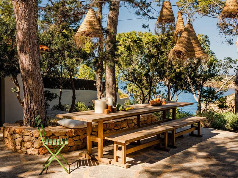 Un espace cuisine extérieure avec une grande table de style ferme et des suspensions marocaines