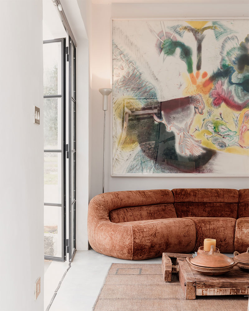 Un salon ouvert avec un canapé vintage Carrera, signé De Pas, D'Urbino et Lomazzi pour BBB Italia, et les œuvres de Jakub Milčák agrémentent le salon. 