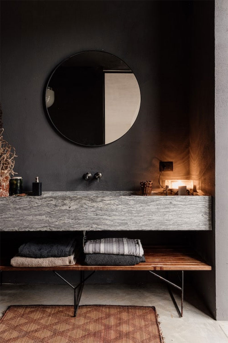 Une salle de bains avec un lavabo en granit sur un mur sombre