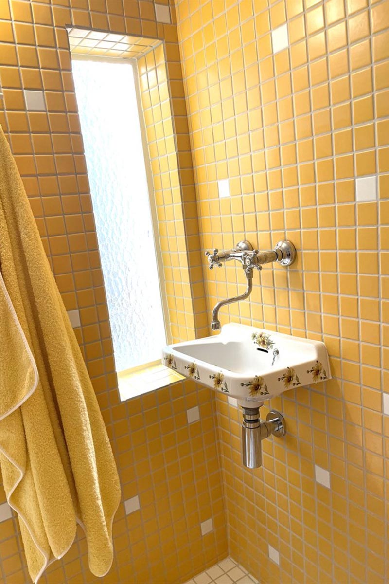 Une salle de bains en petits carreaux de faïence jaune vif