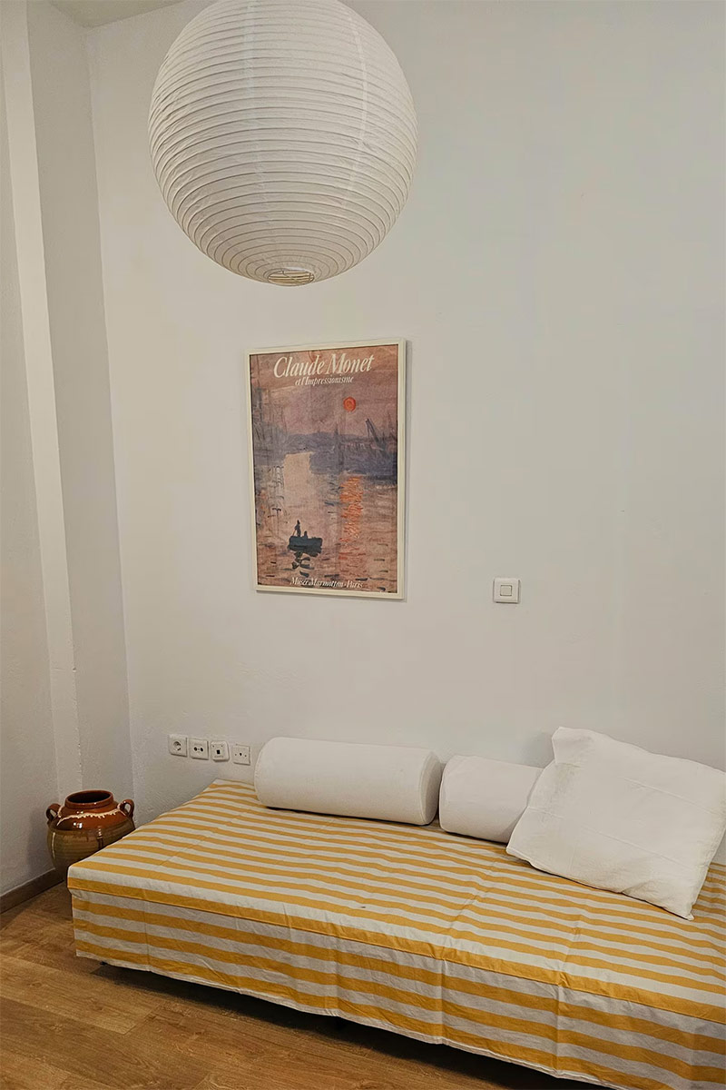 Chambre avec banquette couverte d'un couvre lit à rayures jaune et blanc