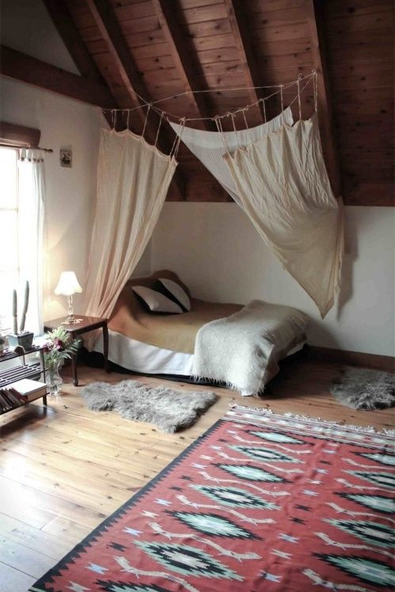 Chambre bohème sous les combles avec ciel de lit et tapis