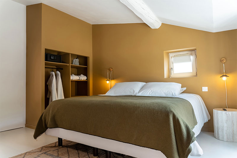 Une chambre avec mur de tête de lit, peint en ocre jaune