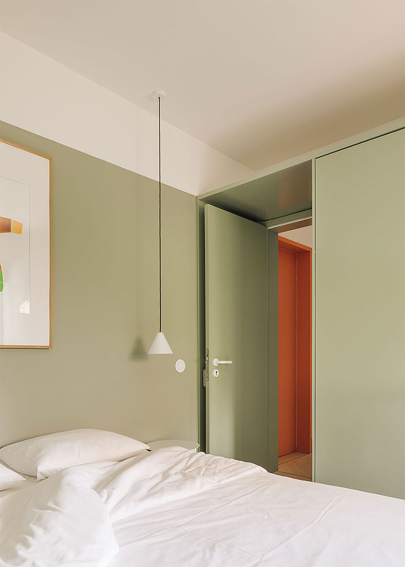 Une chambre design avec une porte lisse, peinte en verte comme les murs de la pièce