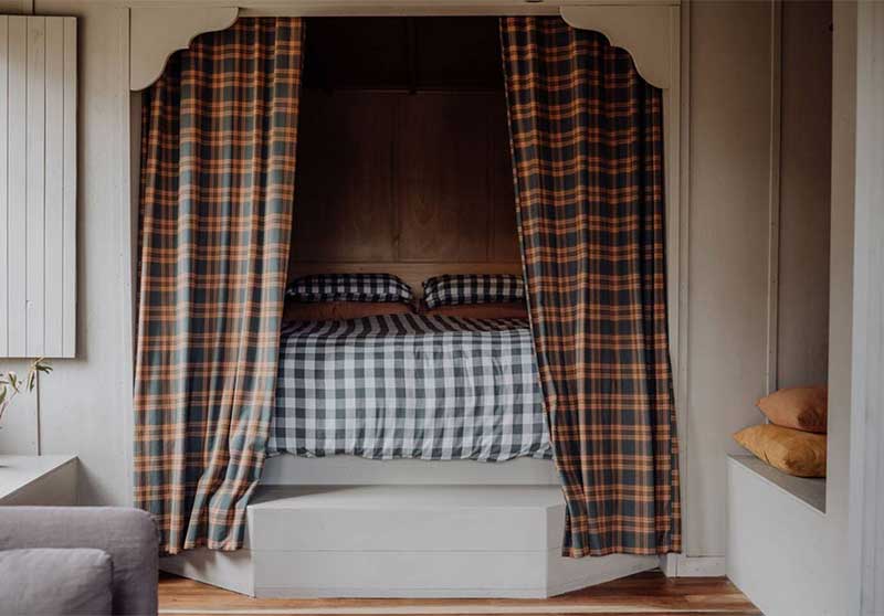 Le lit placé dans une alcôve, refermée par des rideaux écossais Le lit placé dans une alcôve, refermée par des rideaux écossais