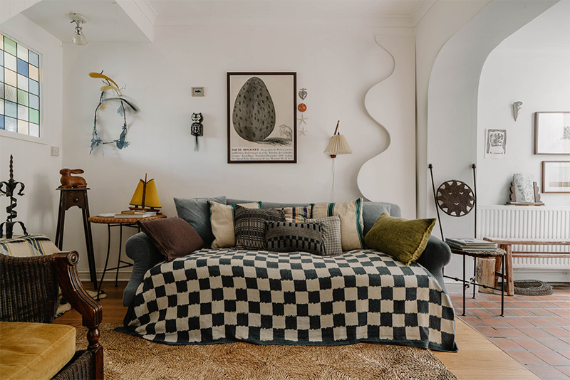 Canapé couvert d'un plaid à damier noir et blanc, avec des coussins aux motifs ethniques Canapé couvert d'un plaid à damier noir et blanc, avec des coussins aux motifs ethniques