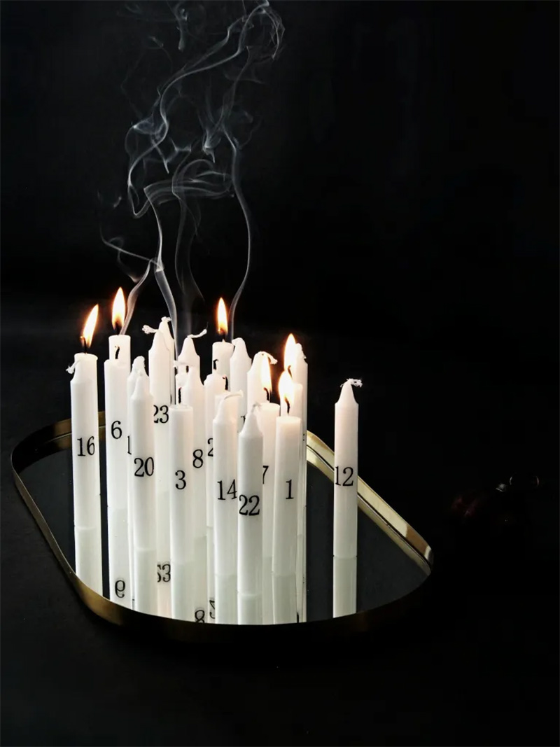 Des bougies de l'avent disposées sur un plateau en vert en centre de table