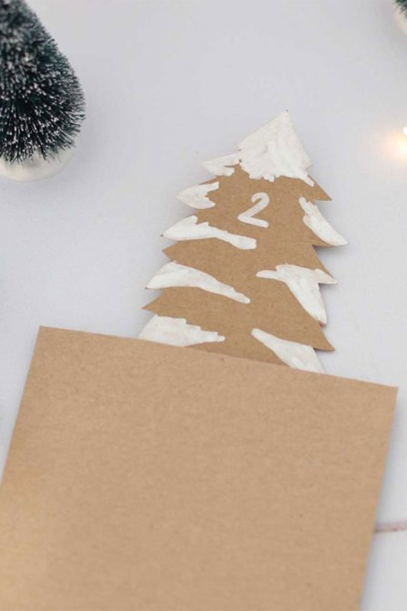 Calendrier de l'avent réalisé à partir de petites pochettes avec sapins découpés, placées dans une boîte