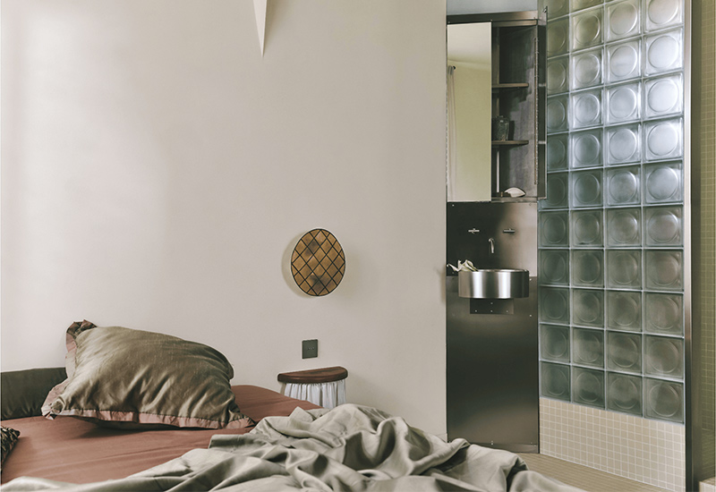 La chambre minimaliste avec sa salle d'eau fermée par des pavés de verre sablés La chambre minimaliste avec sa salle d'eau fermée par des pavés de verre sablés