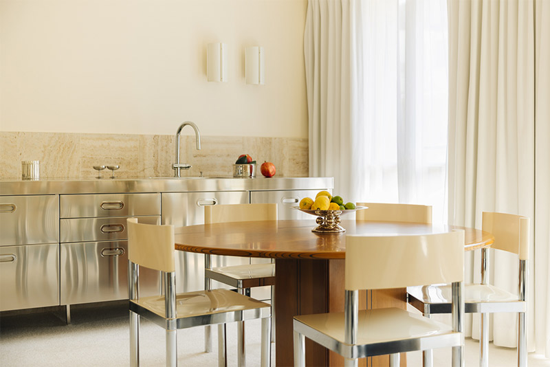 Un appartement peint dans des teintes de glace vanille, accordées avec une cuisine inox et table en bois foncé