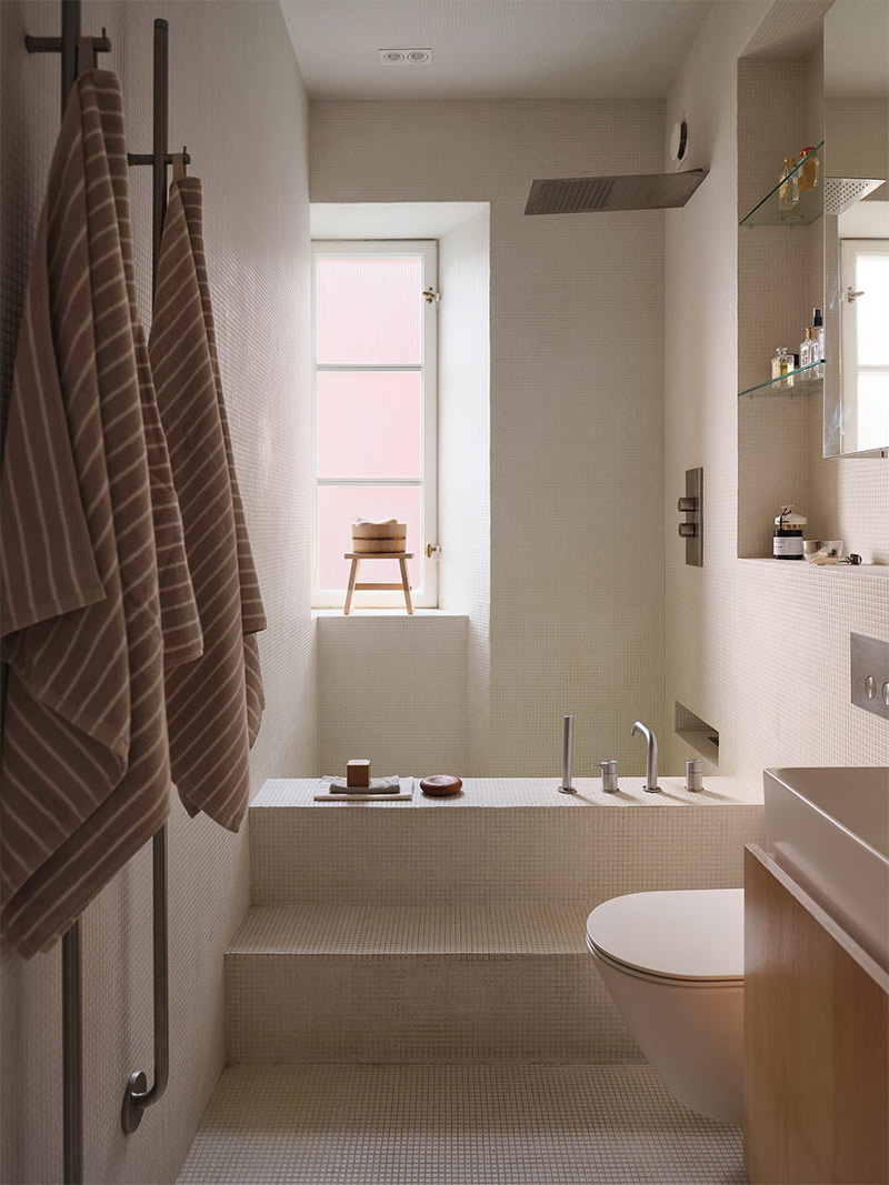 La salle de bains avec sa drôle de baignoire maçonnée qui sert aussi de douche, couverte de micromosaïque blanc crème