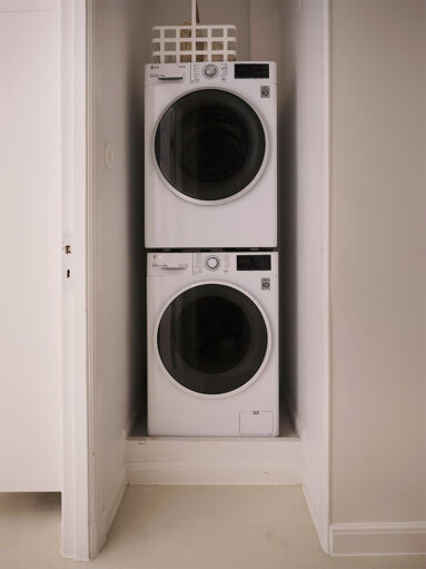 L'idée pratique : le coin buanderie avec ses deux machines lave-linge et sèche posées l'une sur l'autre, encastrées dans une alcôve