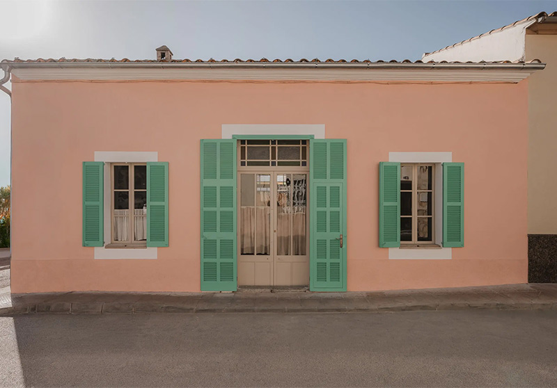 Une maison traditionnelle et modeste à Porto Cristo dans les Baléares avec sa façade couleur pêche et ses volets en persienne peints en vert