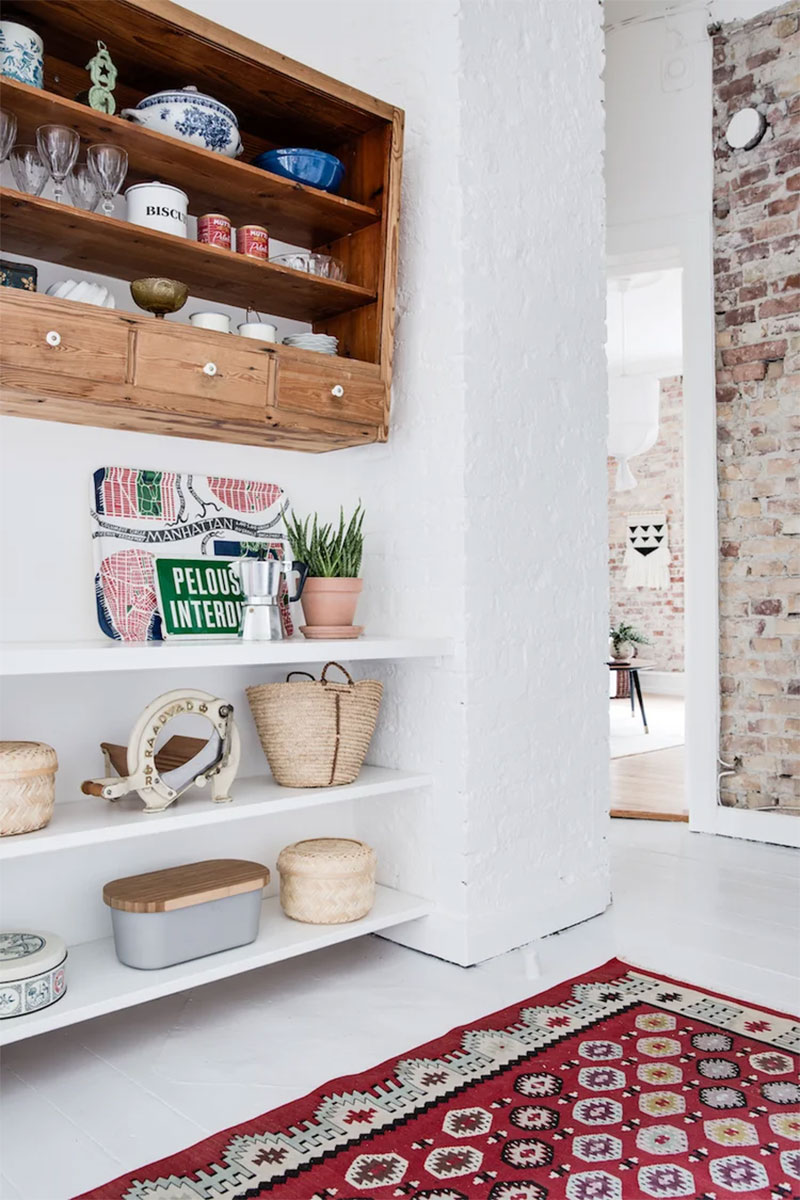 Un intérieur nordique avec des étagères "maison", combinées à un petit meuble mural en bois chiné Un intérieur nordique avec des étagères "maison", combinées à un petit meuble mural en bois chiné