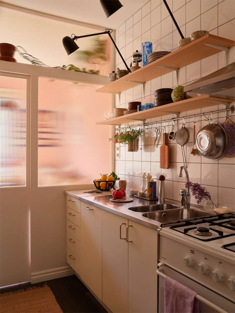 Une cuisine à la fois ordonnée et désordonnée avec des étagères ouvertes et des crochets Une cuisine à la fois ordonnée et désordonnée avec des étagères ouvertes et des crochets