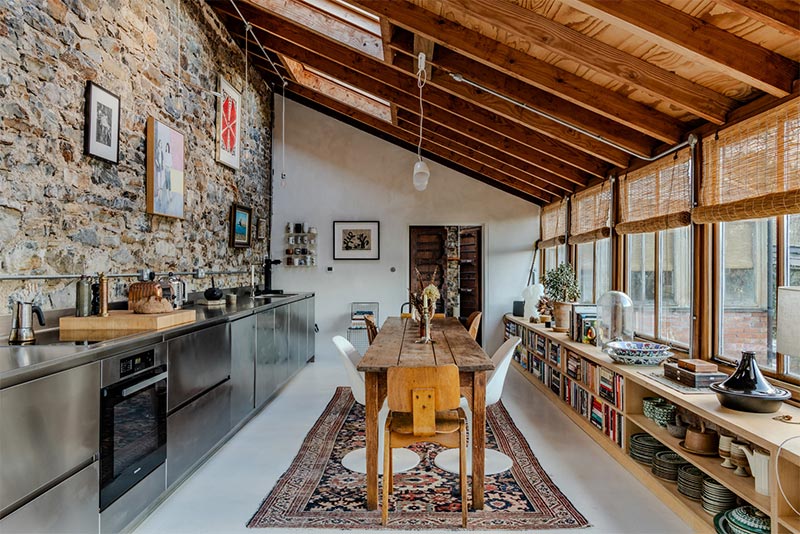 La pièce à vivre, aménagée dans une serre reconstituée avec sa grande table de ferme, dans un style industriel bohème La pièce à vivre, aménagée dans une serre reconstituée avec sa grande table de ferme, dans un style industriel bohème