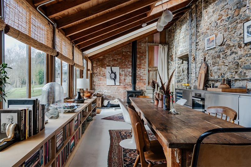 Vue de la pièce à vivre, aménagée dans une serre reconstituée avec sa grande table de ferme Vue de la pièce à vivre, aménagée dans une serre reconstituée avec sa grande table de ferme