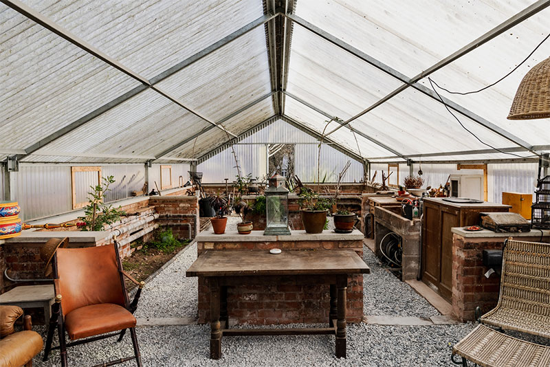 Vue extérieure de la maison et de ses aménagements en bois avec des fenêtres en enfilade Une des serres