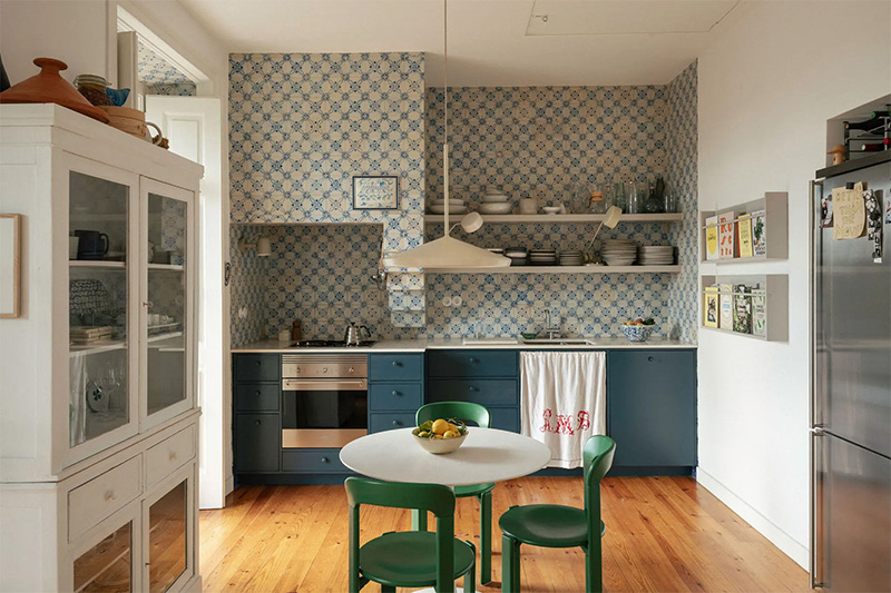 La cuisine, présentant un mur couvert de carreaux anciens type azulejos,complétés de meubles contemporains bleus
