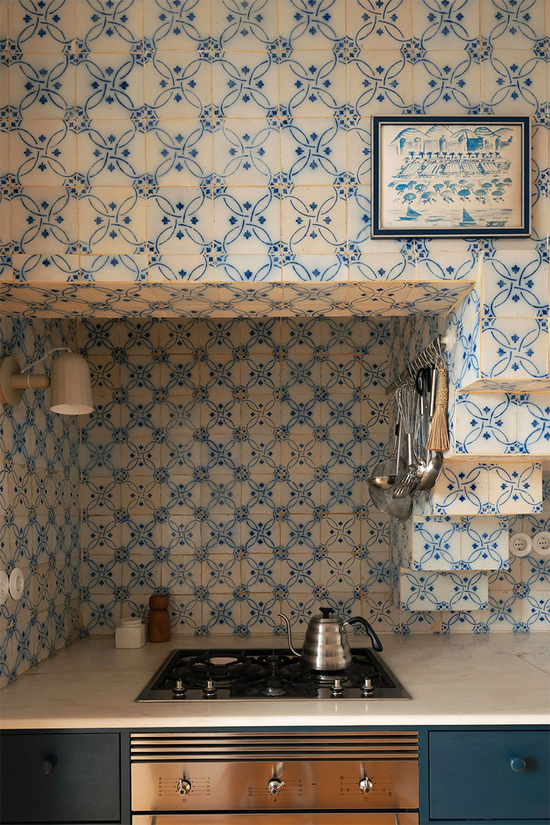 La cheminée de cuisine couverte de carreaux anciens, laissés dans son jus