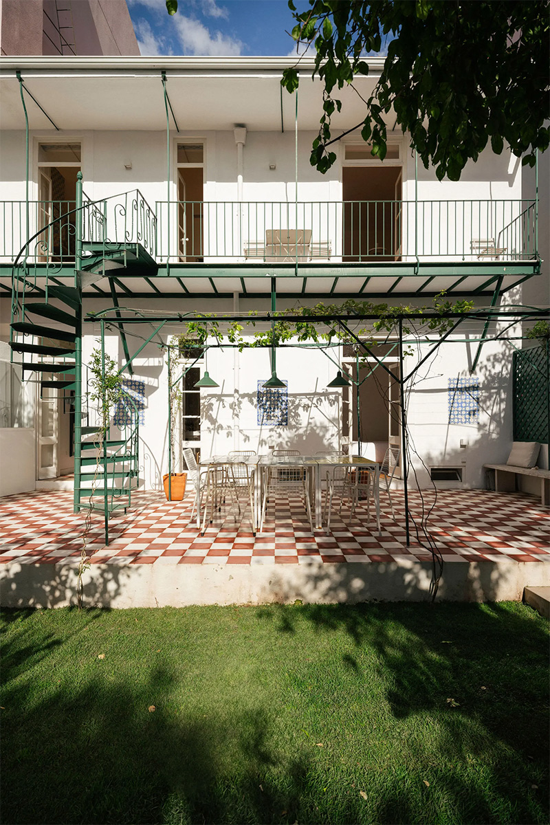 Vue de la façade de la maison, côté jardin, avec sa terrasse et son balcon à l'étage en métal