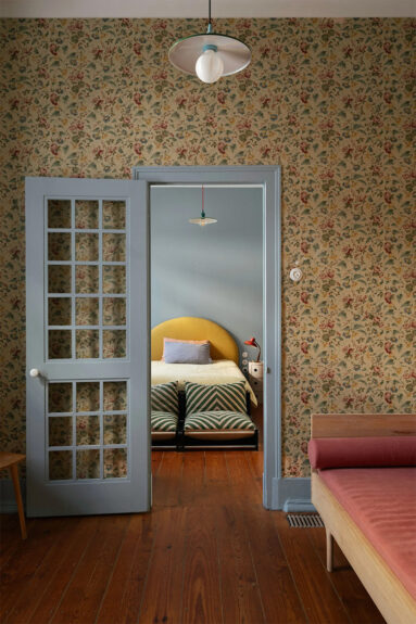 Chambre couverte de papier peint à fleurs d'époque, pimpée par des huisseries peintes en bleu pastel