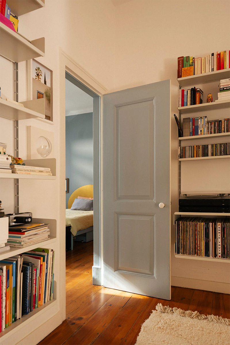 Pièce accueillant des bibliothèques murales, remplies de livres, disques et paperasserie ouvrant sur la chambre bleue