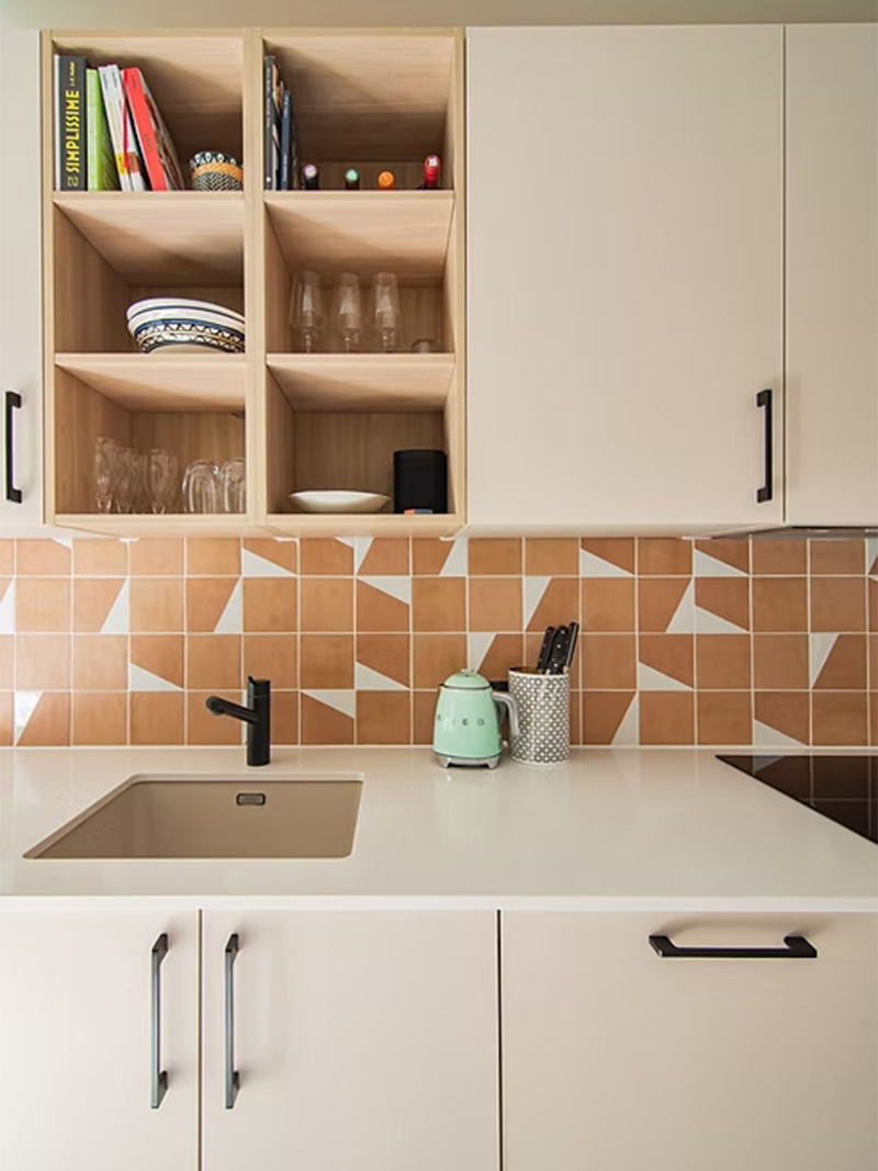 Meubles de cuisine en MDF blanc crème et de travail assorti, relévés par une crédence graphique terracotta et blanc