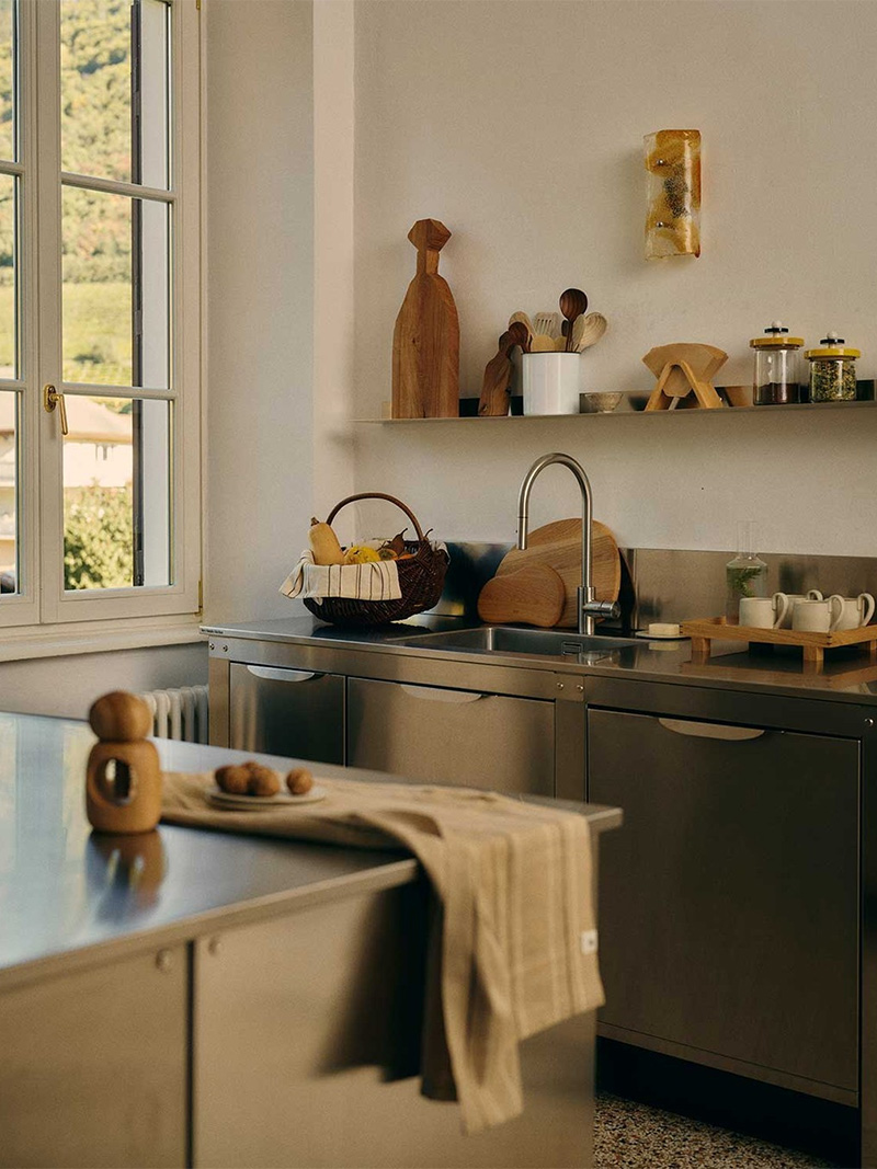 Cuisine professionnelle en block inox sur des murs blans, et beaucoup d'ustensiles en bois