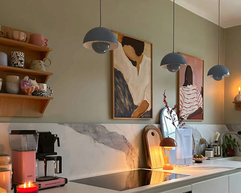 Cuisine blanche minimaliste avec plan de travail et crédence en marbre blanc veiné sur fond de murs vert olive.