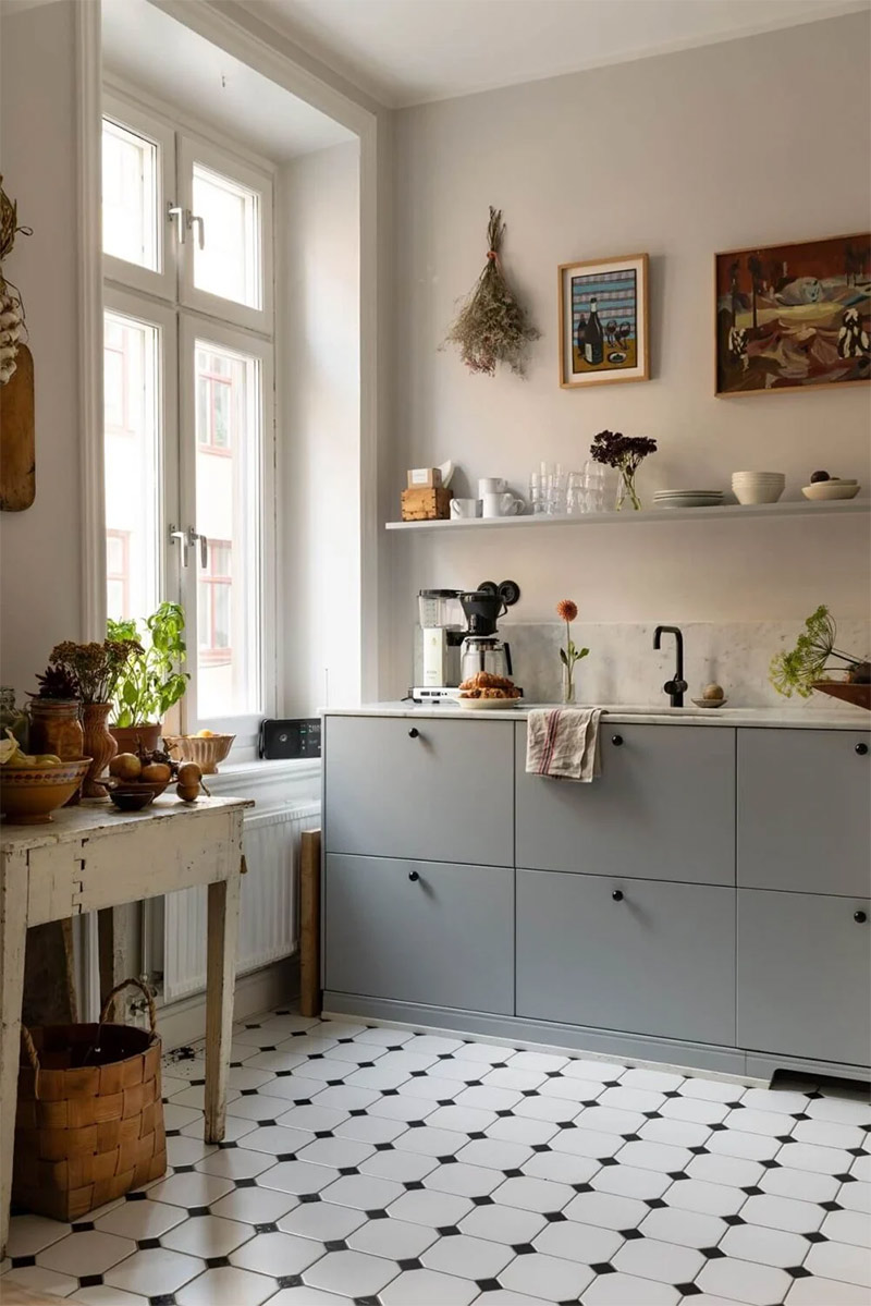 Cuisine minimaliste scandinave à cadres, relevée par un sol à petits cabochons en noir et blanc et des étagères murales accueillant de la décoration