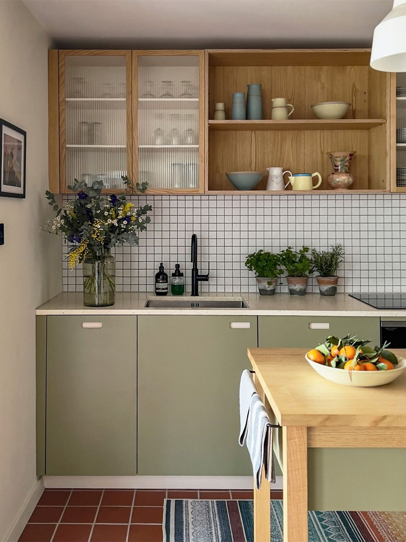 Cuisine moderne vintage avec placards vert olive, meubles hauts en bois, crédence mosaïque blanche et sol en faïence bordeaux.