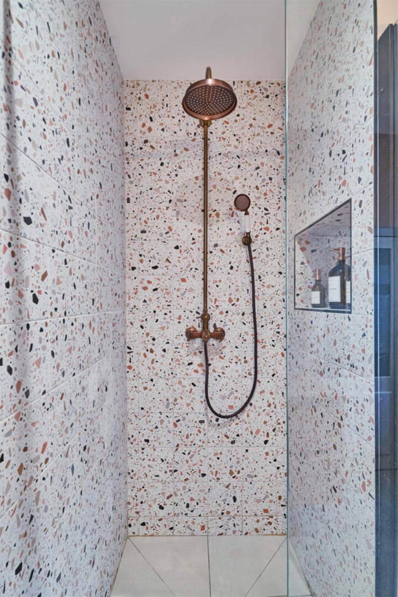 Douche en carrelage Terrazzo avec une colonne de douche en laiton