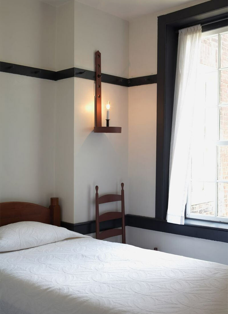 Une chambre shaker avec un éclairage suspendu aux patères murales