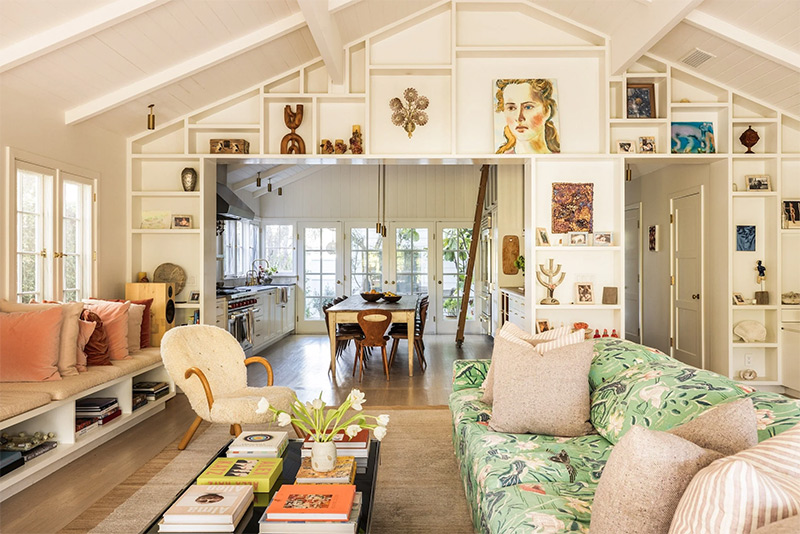 La bonne idée déco : une grande bibliothèque avec des caissons, permettant de mettre en scène des objets entoure les ouvertures reliant la cuisine et l'entrée de la maison