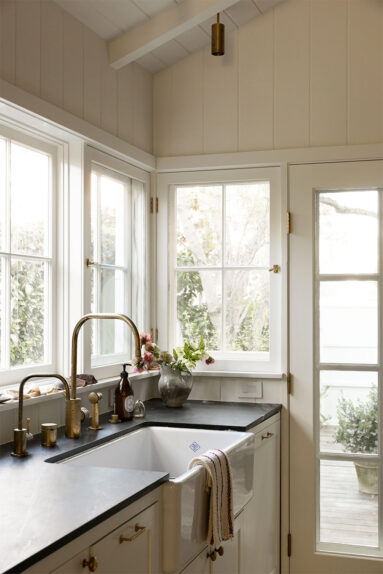 L'évier est placé devant des fenêtres, reliant l'intérieur à la terrasse extérieure