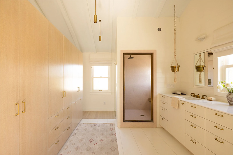 La salle de bains présente une ambiance monochrome de blanc crème avec un long mur dressing