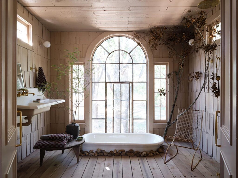 La salle de bains avec sa baignoire incrustée et sa baie vitrée récupérée qui crée une mise en scène extraordinaire