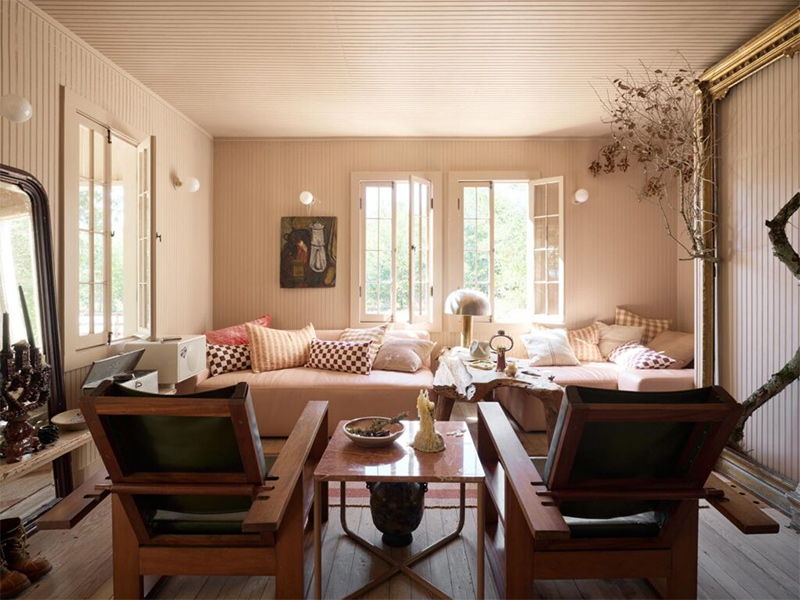 Le salon tout en lambris de bois, peint en beige, aménagé avec du mobilier chiné