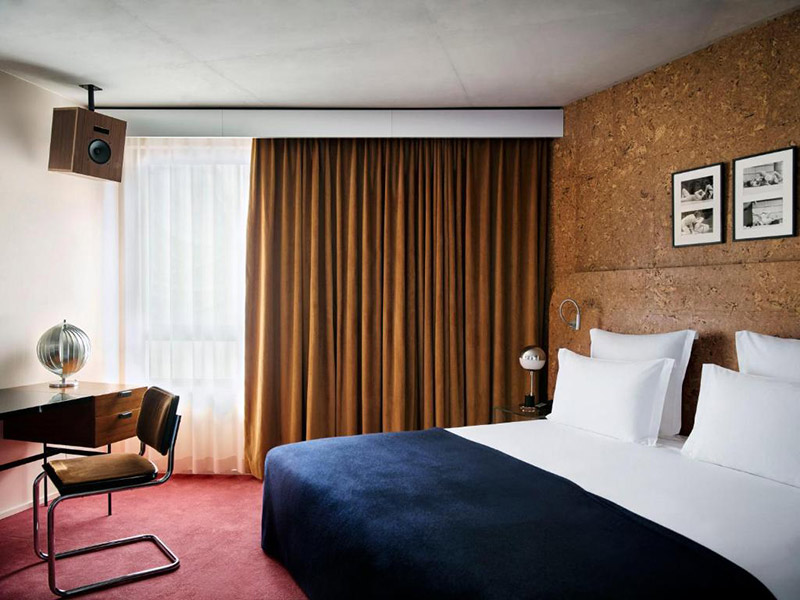 La suite 63 de l'hôtel Bus Palladium avec sa moquette rouge rosé, ses murs en lièges, et ses rideaux en velours ocre