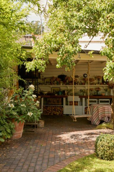 Un préau, aménagé au fond du jardin, en une pièce à vivre avec une cuisine aménagée d'extérieure