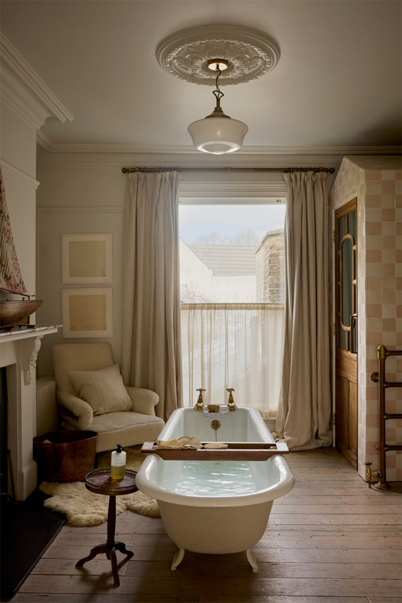 La salle de bains pensée comme un salon avec baignoire îlot à pieds de lion, fauteuil et tapis généreux