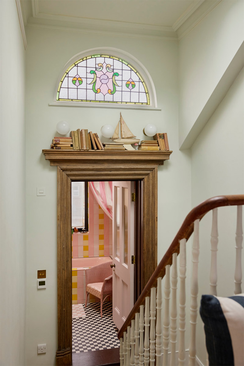 La cage d'escalier de la maison avec vue sur la salle de bains en damier de zelliges rose, jaune et crème