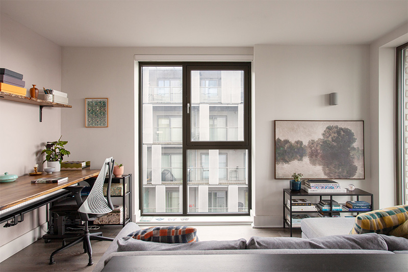 Petit séjour complexe avec ses deux portes vitrées, accueillant un bureau, un coin salon et un espace repas