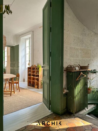 Vue du palier donnant sur la salle à manger dont le plancher a été peint en blanc et les portes en vert printannier