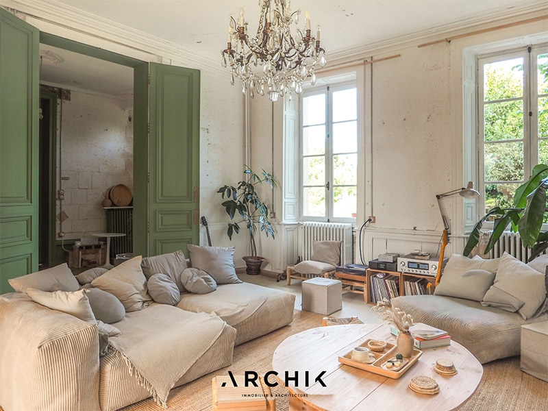 Le salon du château de Dirac dans un style slow bohème entre lustre à pampilles et canapé poufs