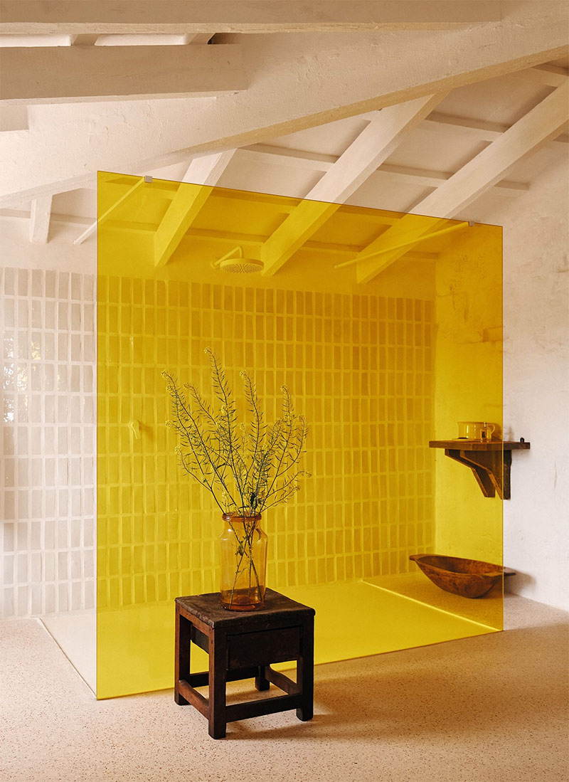 Panneau en verre coloré jaune, fait office de paroi de douche dans cette maison à Minorque Panneau en verre coloré jaune, fait office de paroi de douche dans cette maison à Minorque