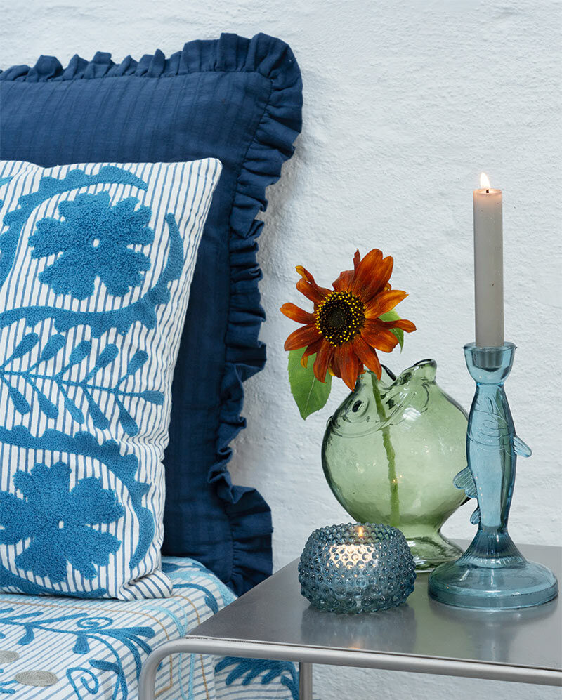 Madam Stoltz, collection été 2026 : Table d'appoint, décorée de vases en verre coloré Madam Stoltz, collection été 2026 : Table d'appoint, décorée de vases en verre coloré pour banquette réalisée avec des textiles bohèmes dans les tonalités de bleu